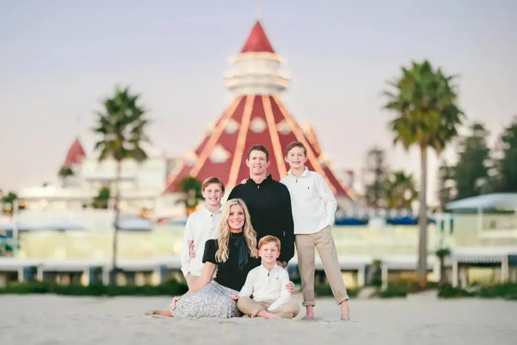 Family on the beach in front of the Hotel del Coronado's red turret at dusk