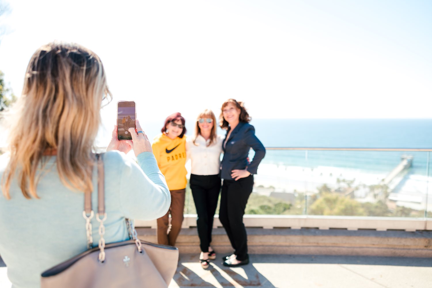 Concierge friends being photographed on the rooftop terrace with La Jolla Shores and Scripps Pier behind them