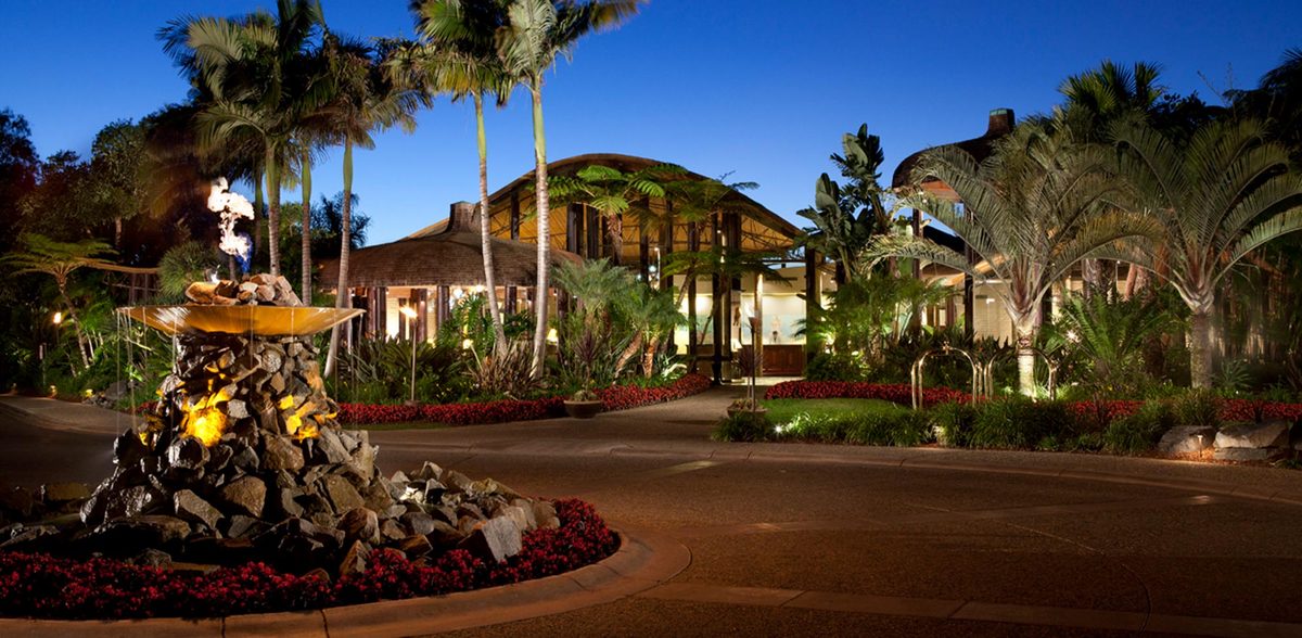 Paradise Point Resort and Spa entrance at night with illuminated fountain and tropical palm trees