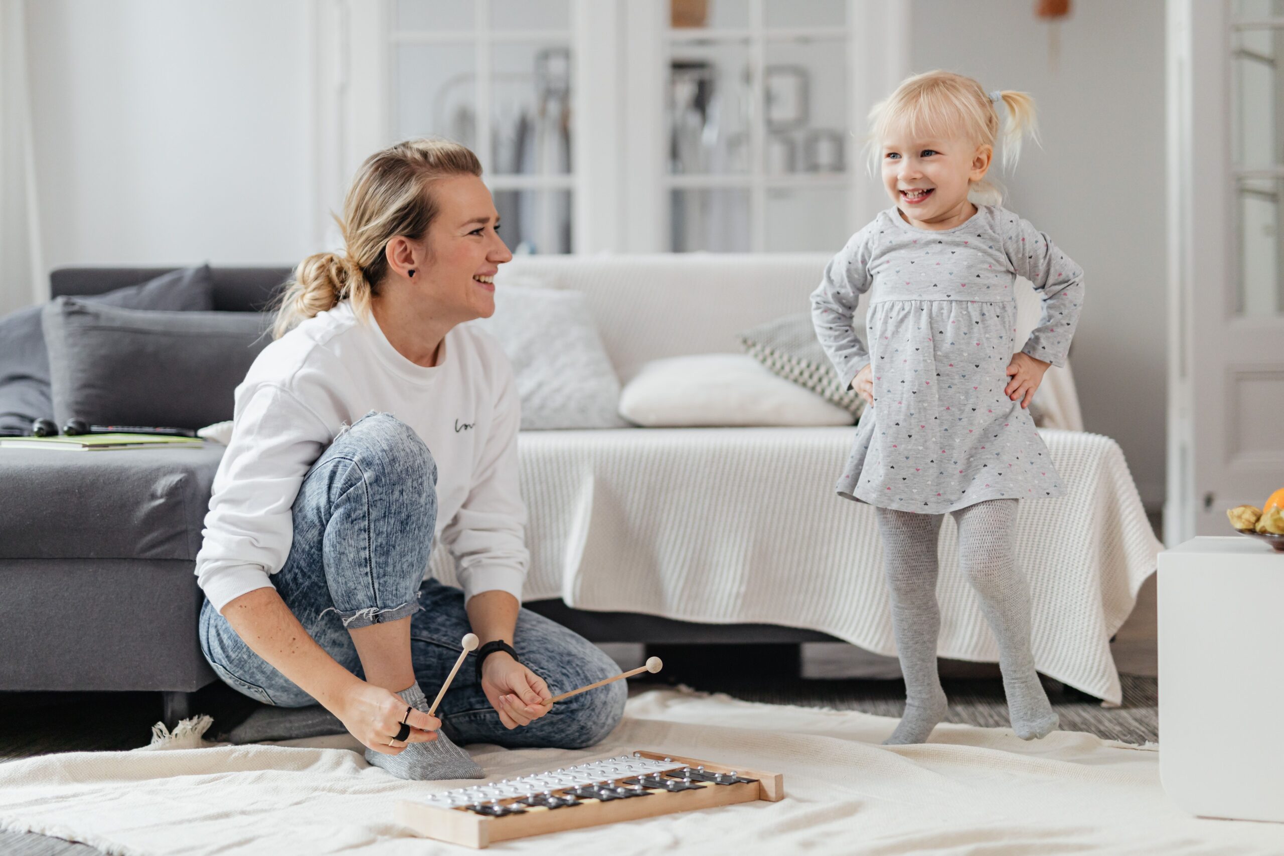 Caregiver playing xylophone with a happy toddler