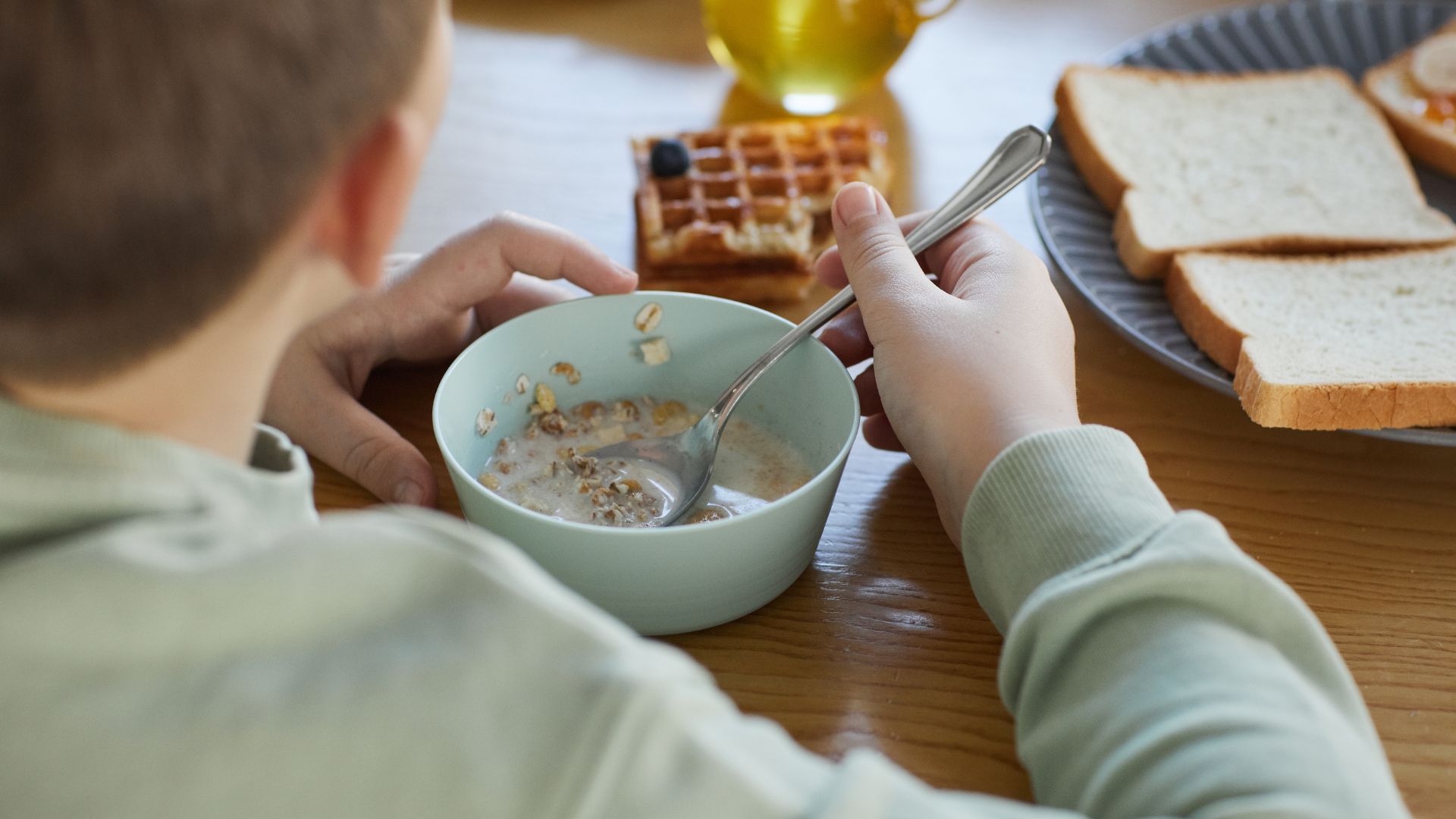 Child eating breakfast at the table during a school morning practice run