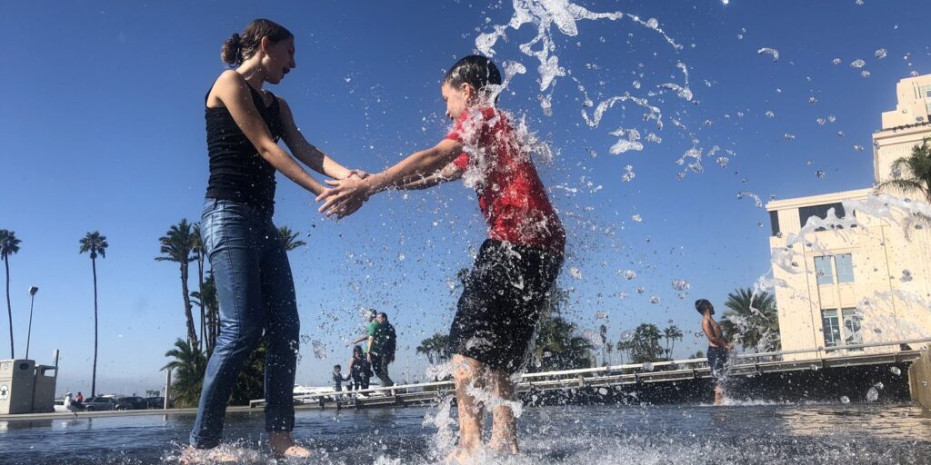 Two kids splashing in the fountain at Waterfront Park in downtown San Diego