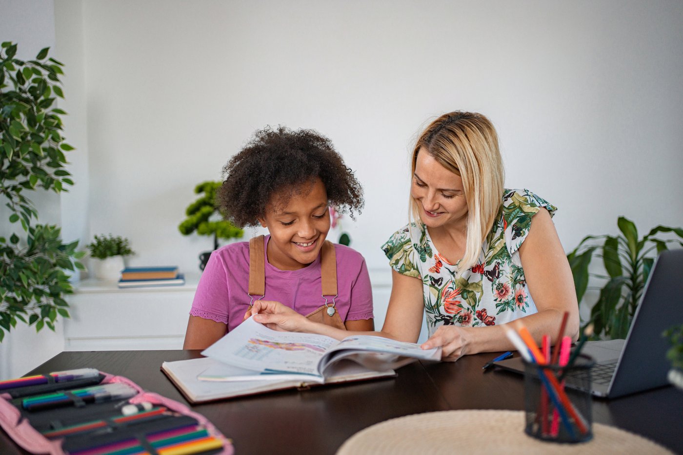 Caregiver helping a child with homework at the kitchen table after school