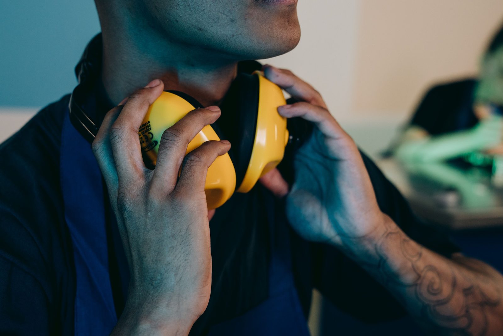 An adult fitting bright yellow protective ear muffs onto someone's head