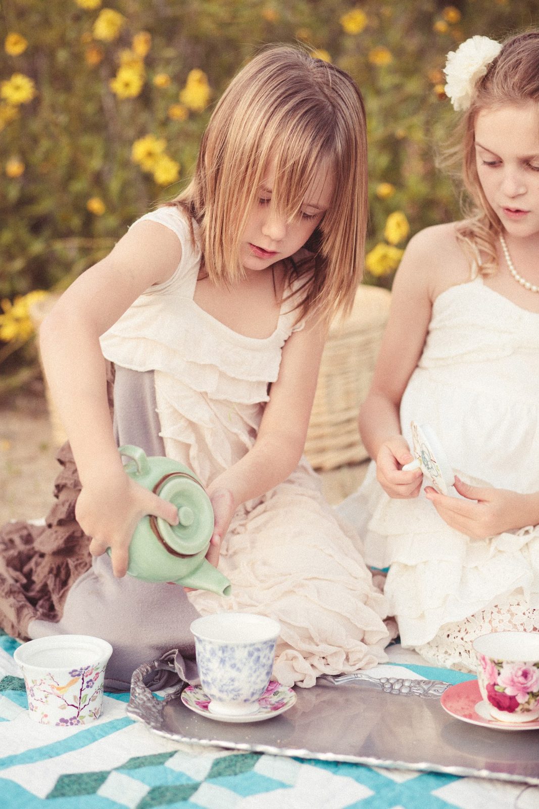 Two girls pour tea outdoors during a vacation babysitting picnic