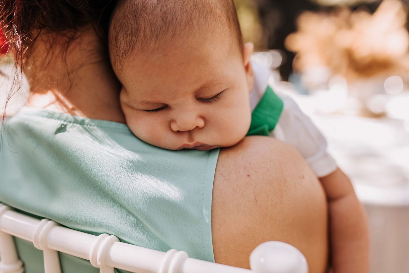 A sleeping baby resting on a parent's shoulder